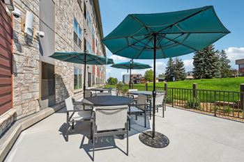 A patio with a table and chairs under a large umbrella.